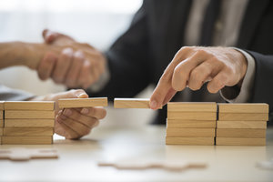 Photo of people shaking hands while building blocks.