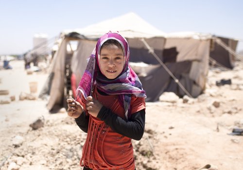 A young girl outside in front of a tent.