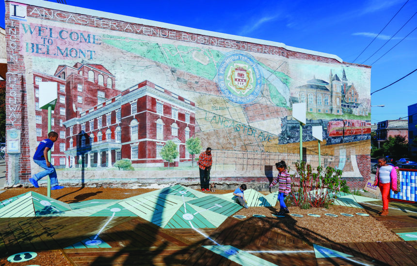 People playing in front of a mosaic in Belmont