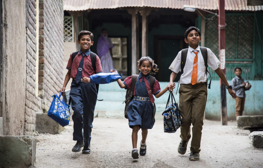 3 kids walking to school, smiling