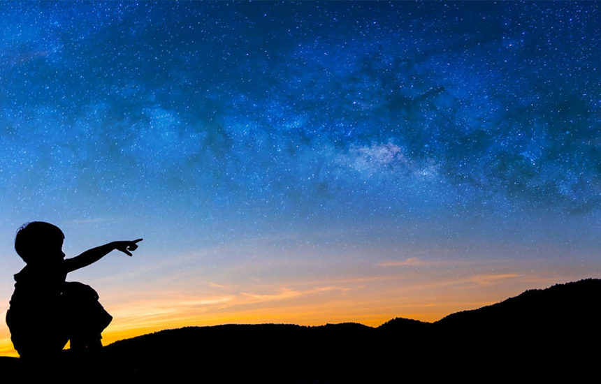 A boy pointing at the night sky