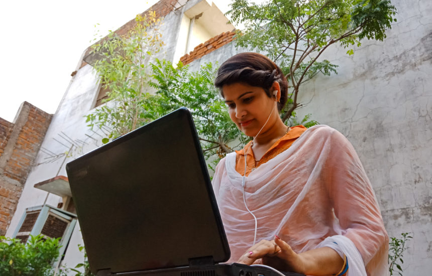 A woman with headphones in working on a laptop