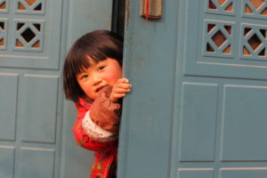 A happy child looking out of a doorway.