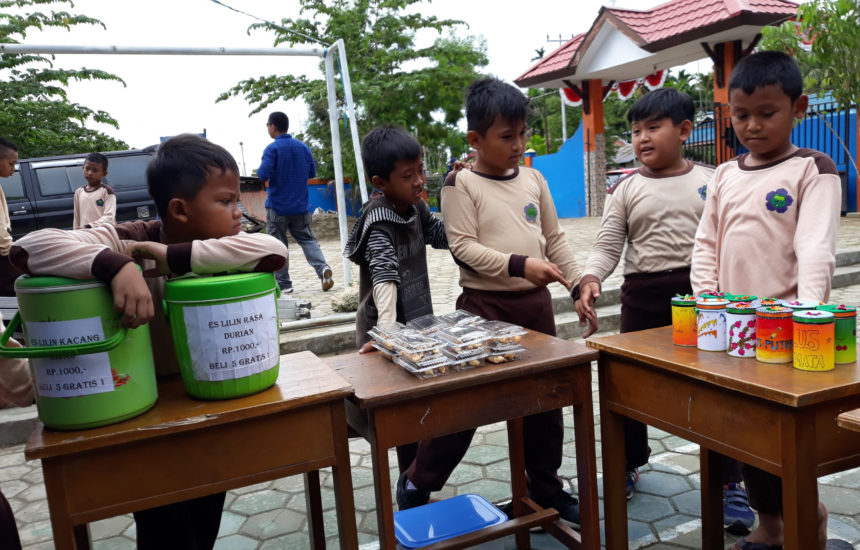 A group of kids gathers around tables outside