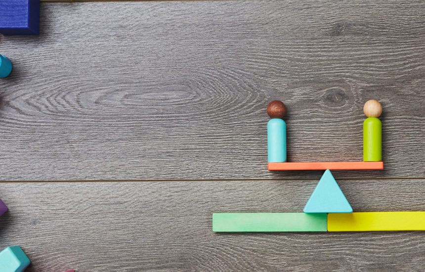 Blocks in the shape of a scale with two equal blocks representing people on it