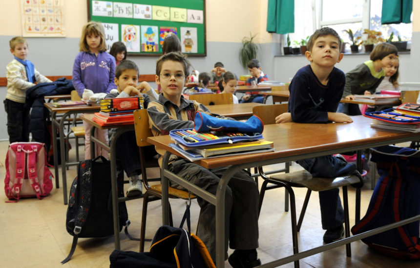 Children in a classroom, sitting at tables in pairs