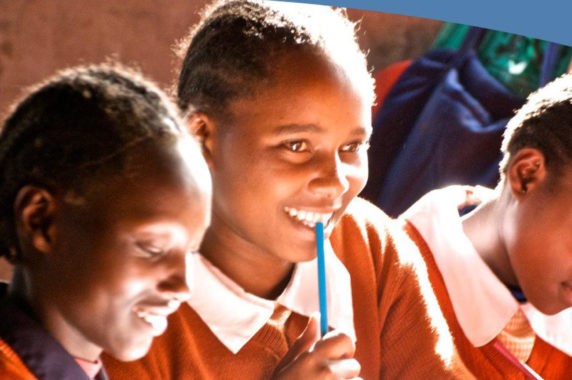 A group of kids smiling and writing