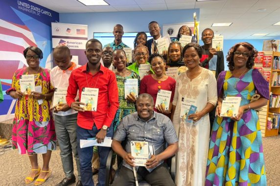 Group of smiling educators in Cote d'Ivoire, holding certificates from the training they completed.