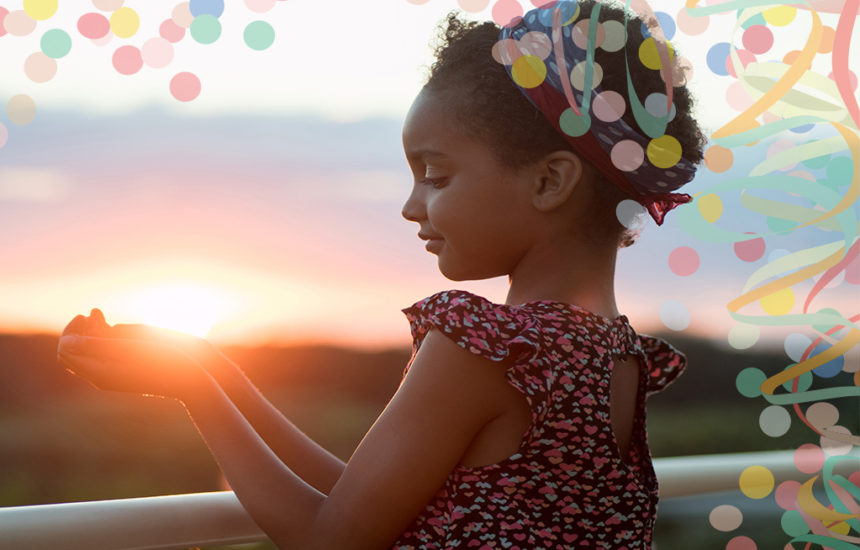 A girl smiles and puts out her hands to look like she's holding the sun