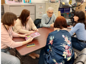 Group of people talking at shared desk.