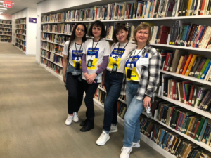 Four woman smile for photo in front of large book shelf