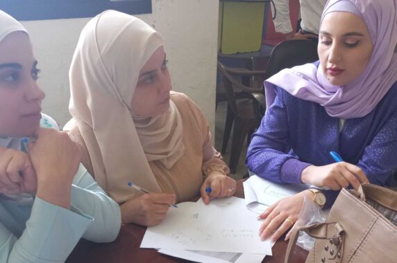 Three women collaborating and writing shared notes.