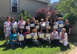 Group of Ukrainian educators standing outside a building, holding certificates of completion