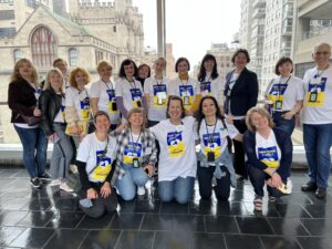 A group of Ukrainian educators and CE International staff members standing in a hallway with the New York City skyline out the window behind them