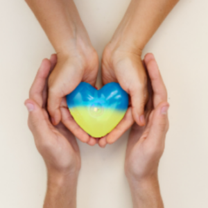 A pair of grown-up and a pair of child hands, together holding a blue-and-yellow heart