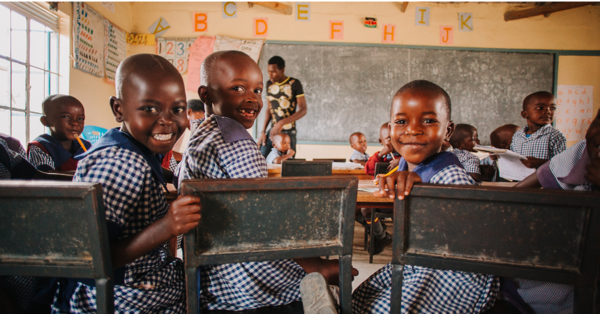 Three smiling children in a classroom in Africa