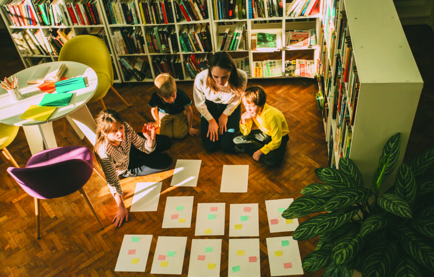 Children working with adults on a paper mapping project on the floor