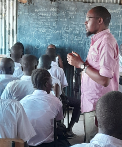 Photo of Fredrick in the classroom with students looking at the blackboard