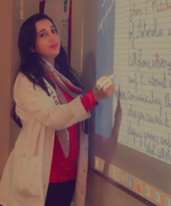 Photo of Soukaina in the classroom, writing on a whiteboard