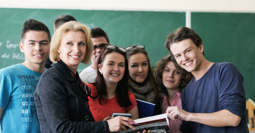 Smiling teach with high school students in a classroom