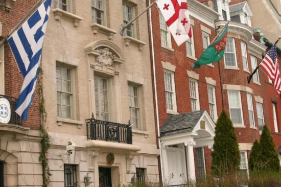 A row of embassies with various national flags flying in front of them.