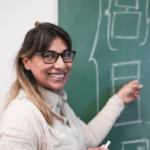 Teacher smiling by a chalkboard