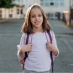 Happy girl wearing a backpack in front of her school in Serbia