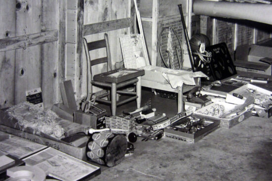 A black-and-white historical photograph of materials sent to support learning, including a chair with books and other items around it.