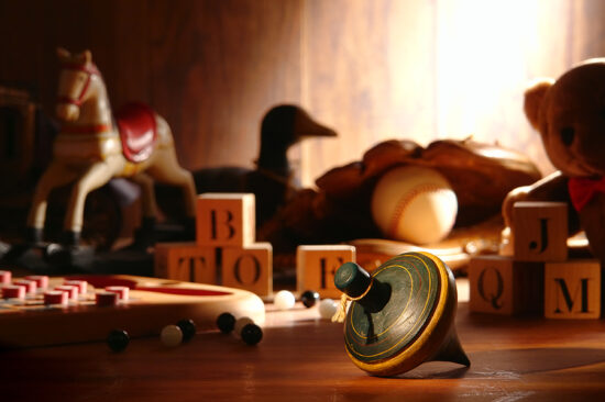 A collection of toys on the floor, including a rocking horse, a spinning top, building blocks, and more.