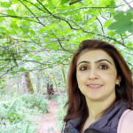 Headshot of Harveen Kaur, a Project Fellow in the Pathways to Teaching Project. In the photo, she is in the woods, surrounded by nature and leaves