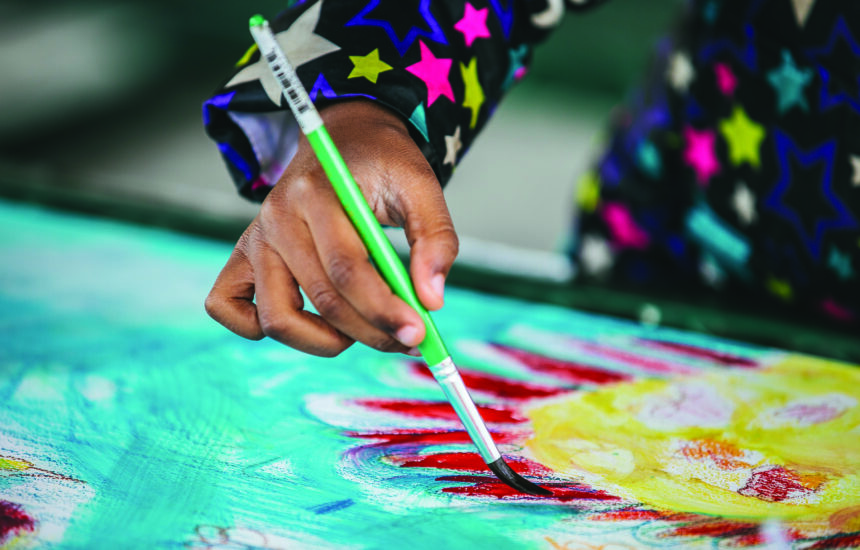 Photo of a student using a paintbrush to paint a planet.