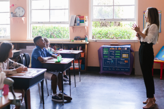 A teacher happily teaching in a classroom.