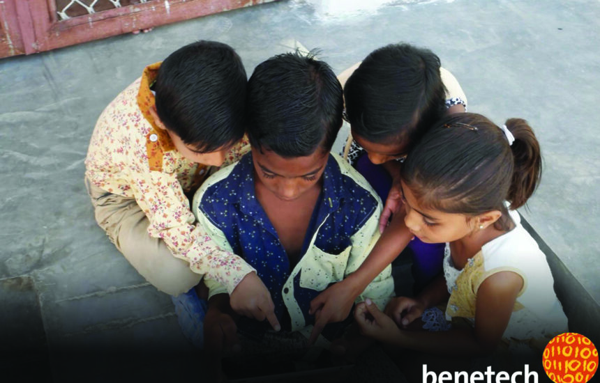 Visually impaired children gathered around Benetech reading solution.