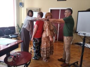 Four teachers standing together, doing an activity where two of them hold hands to enclose the other two inside of a circle.