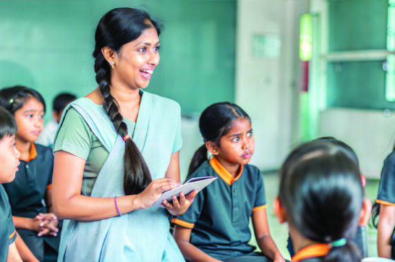 A smiling teacher with students in her classroom.