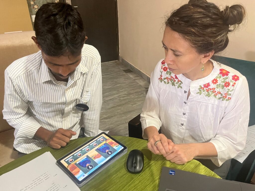 Two people sit at a table, looking at a tablet with images from the Coach Up app on the screen.