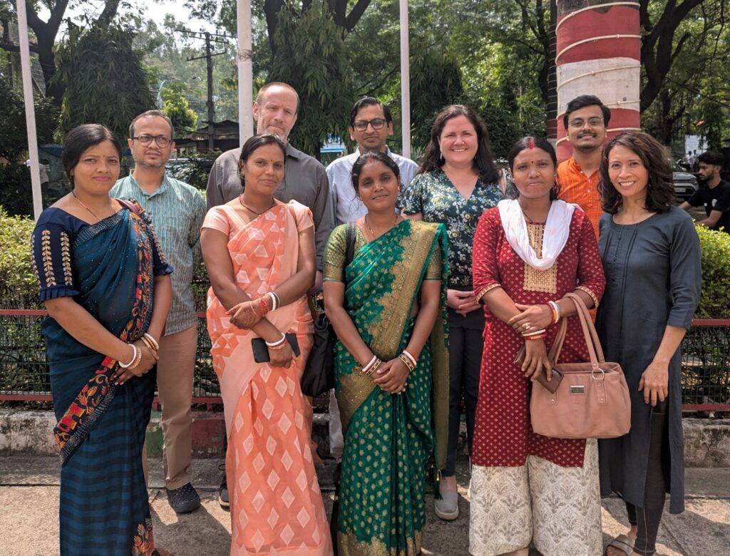A group of people standing outside, smiling.