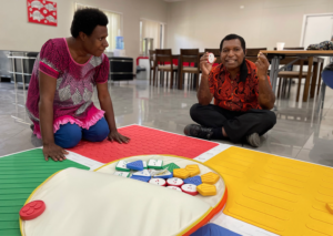 A teacher with vision impairment (in the red shirt) touching and feeling the Reach & Match components.
