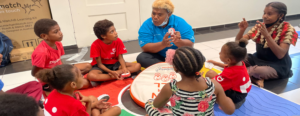 An educator leads a small group learning activity with children seated in a circle, using hands-on educational materials.