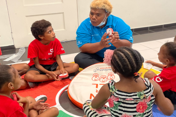 An educator leads a small group learning activity with children seated in a circle, using hands-on educational materials.