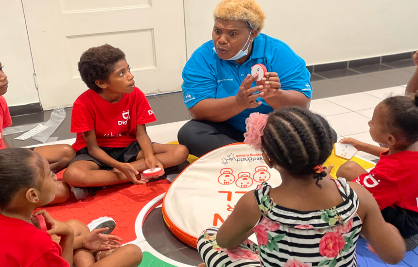An educator leads a small group learning activity with children seated in a circle, using hands-on educational materials.