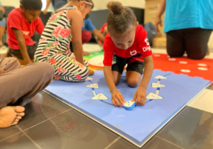 A young child plays with the components of a Reach & Match game. 